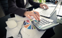 image of desktop showing person working on both laptop and calculator