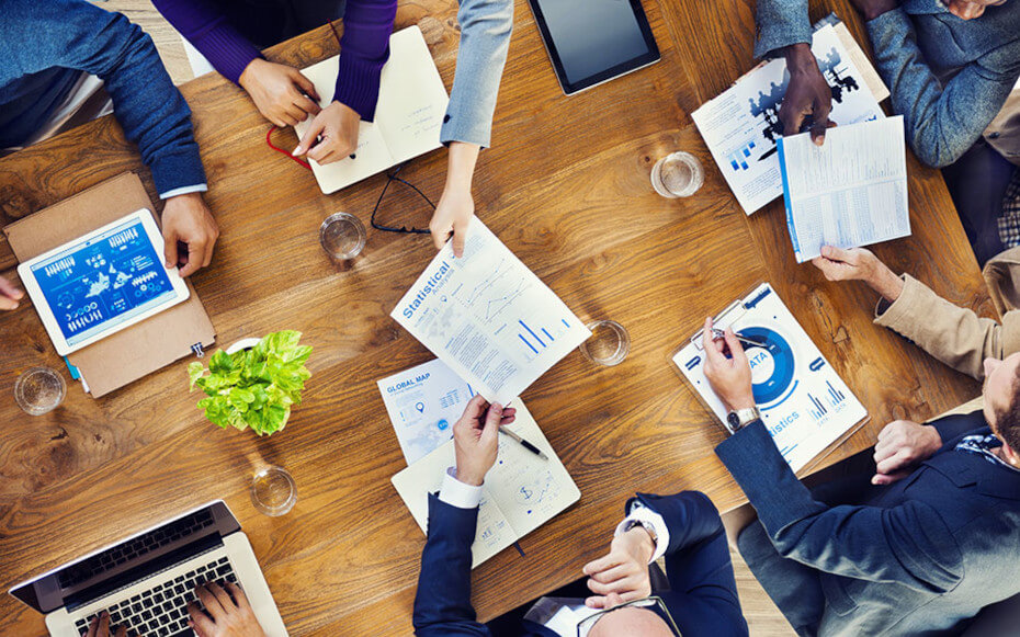 A group of people around a table comparing data.