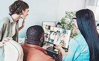 Young professionals in the office attend a virtual meeting with coworkers who are working remotely.