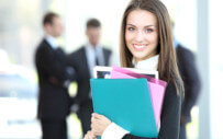 A woman carries some file folders containing her company's onboading plan.