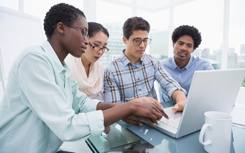 group of men and women looking at a laptop