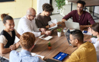 A female intern at a table of mostly men.