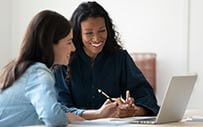 Two women collaborate at a computer.