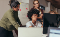 A group of interns work on a project at a PC.