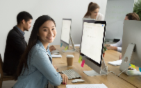 students at a large desk working on separate computers